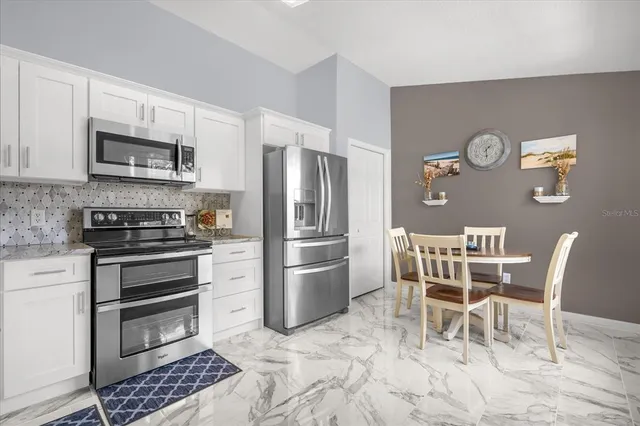 a kitchen with stainless steel appliances kitchen island granite countertop a refrigerator and a stove top oven