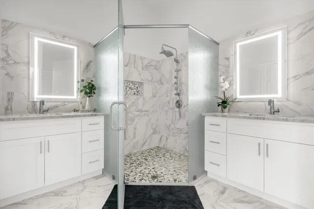 a bathroom with a granite countertop sink a mirror a vanity and a shower
