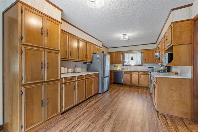 a kitchen with stainless steel appliances granite countertop a refrigerator a sink dishwasher and a stove with wooden floor