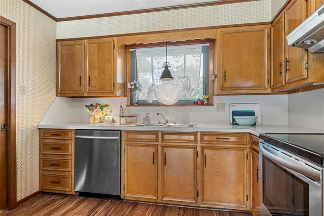 a kitchen with stainless steel appliances granite countertop a sink and cabinets with wooden floor