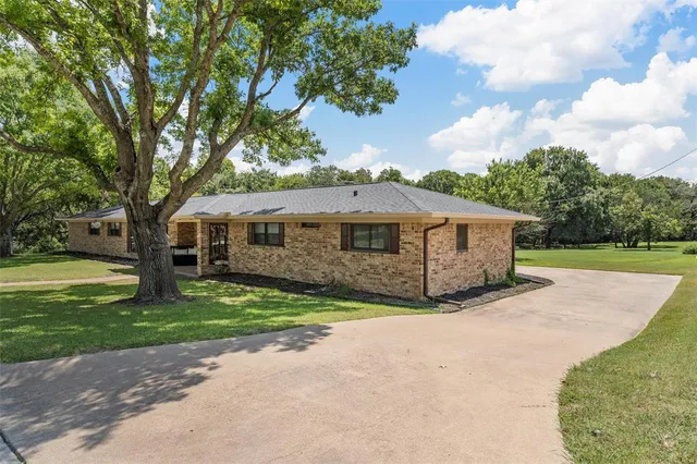 a view of a house with a big yard and large trees