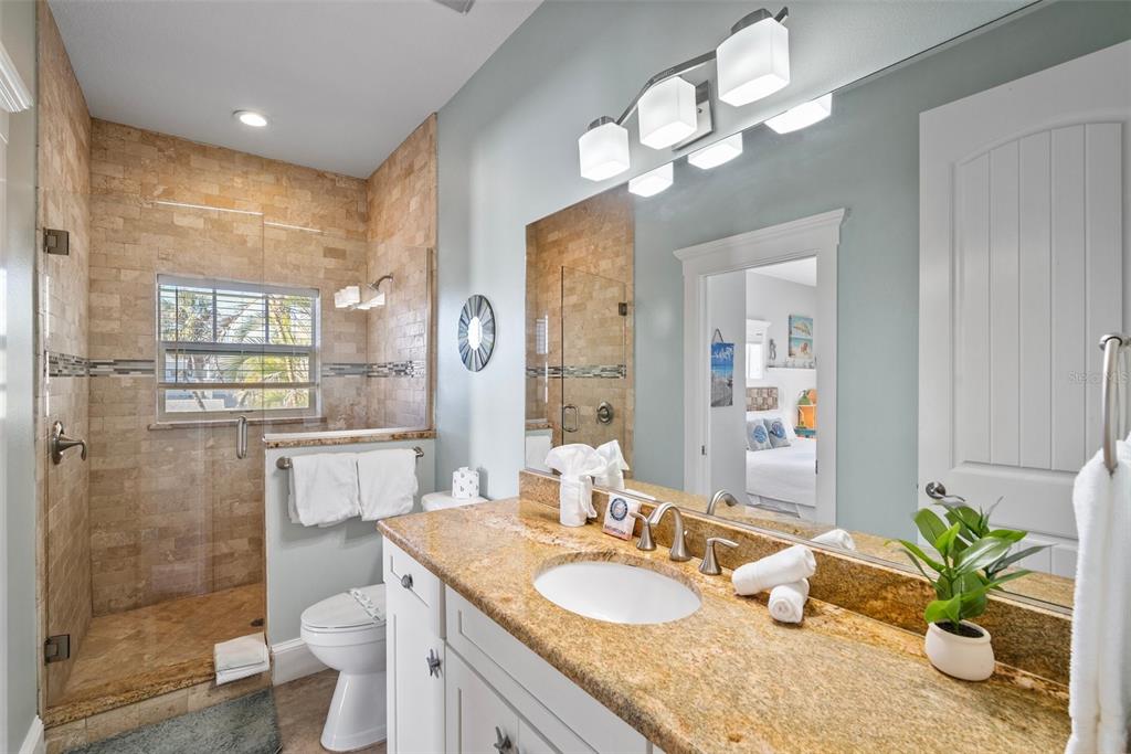 204 66th Street Holmes Beach, FL 34217 - Photo 19 of 53 a bathroom with a granite countertop sink a toilet and a mirror