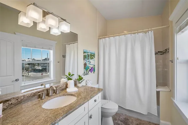 a bath room with a granite countertop sink a toilet and bathtub