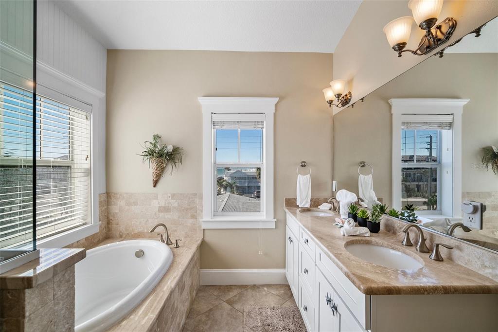 204 66th Street Holmes Beach, FL 34217 - Photo 34 of 53 a bathroom with a granite countertop tub a double vanity sink a vanity and a large mirror