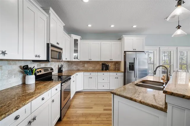 a kitchen with granite countertop a sink stainless steel appliances and cabinets