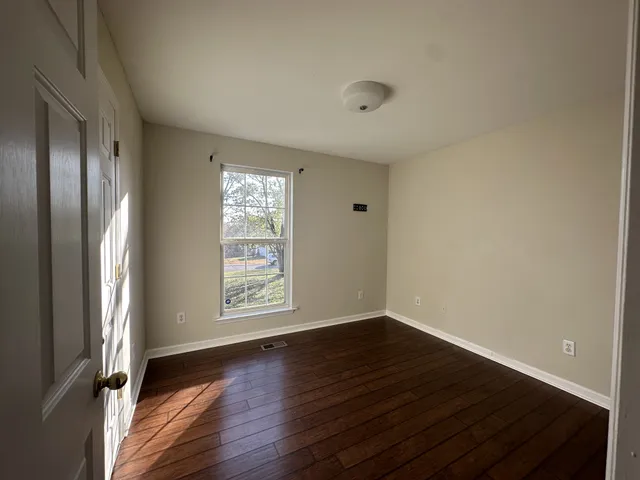 an empty room with wooden floor and window
