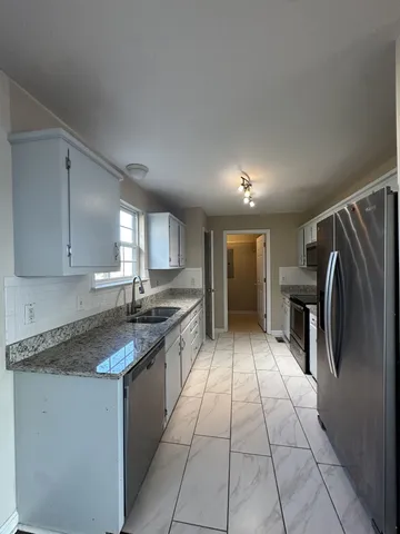 a kitchen with granite countertop a stove a sink and a refrigerator
