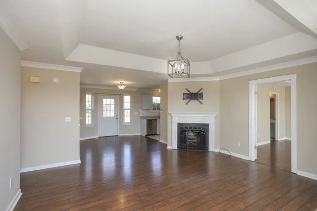 a view of a livingroom with a fireplace wooden floor and chandelier