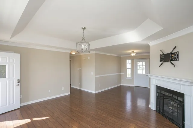 a view of a livingroom with a fireplace wooden floor and chandelier