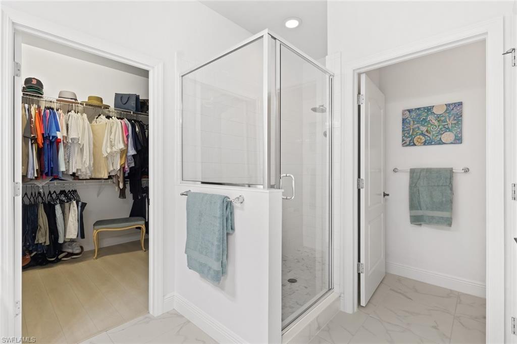 6973 Avalon Circle, Unit 1406 Naples, FL 34112 - Photo 15 of 36 Full bathroom featuring a stall shower, a spacious closet, and light marble finish floors