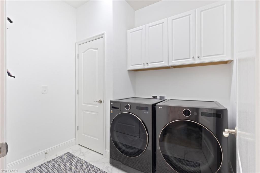 6973 Avalon Circle, Unit 1406 Naples, FL 34112 - Photo 21 of 36 Laundry area with washer and clothes dryer, light marble finish floors, and cabinet space