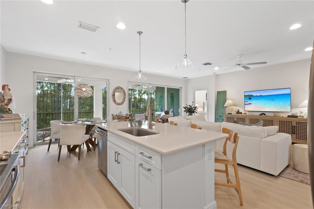6973 Avalon Circle, Unit 1406 Naples, FL 34112 - Photo 36 of 36 Kitchen with white cabinetry, open floor plan, light wood-type flooring, pendant lighting, and stainless steel appliances