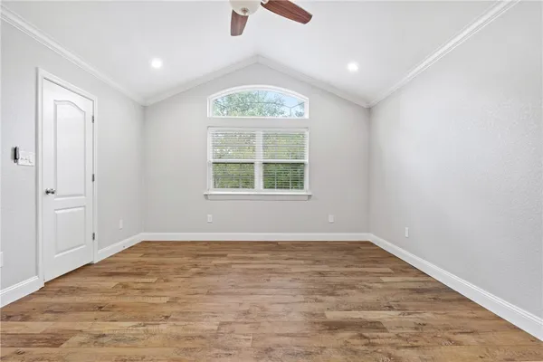 an empty room with wooden floor cabinet and windows