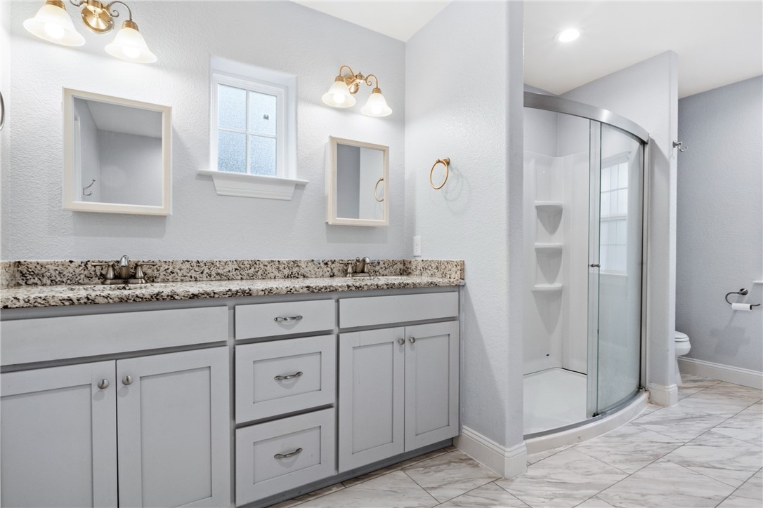275 Woodruff Road Waco, TX 76705 - Photo 25 of 42 a bathroom with a granite countertop sink a mirror and a shower
