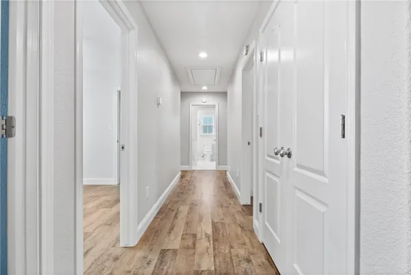 a view of a hallway with wooden floor and a bathroom