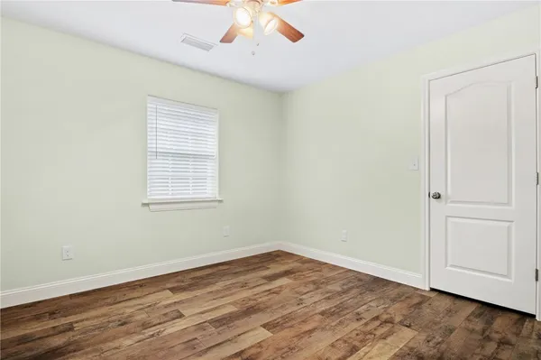 an empty room with wooden floor cabinet and windows