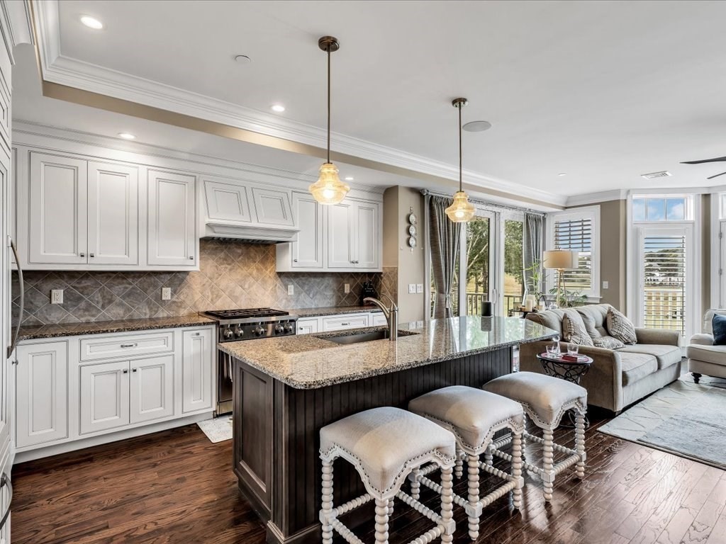 70 Simons Road, Unit C Mashpee, MA 02649 - Photo 4 of 23 a kitchen with granite countertop a sink a center island a stove and a wooden floors