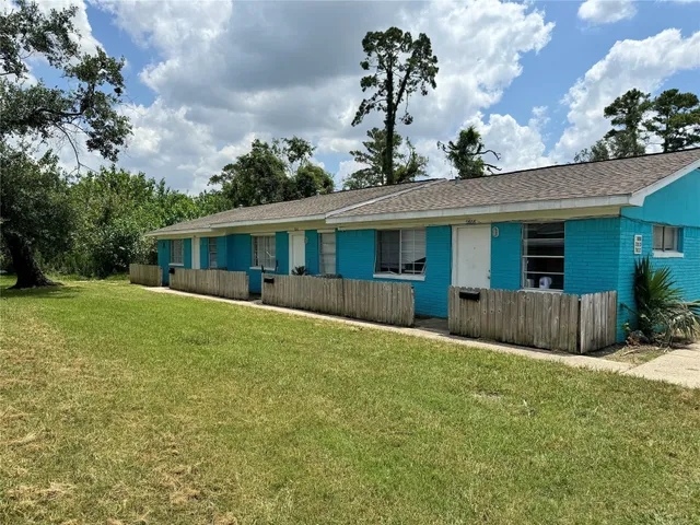 a view of a house with a yard and potted plants