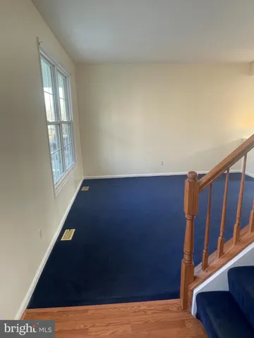 a view of an empty room with wooden floor and stairs