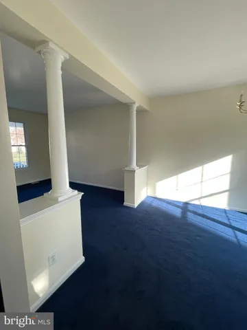 a view of an empty room with wooden floor and stairs