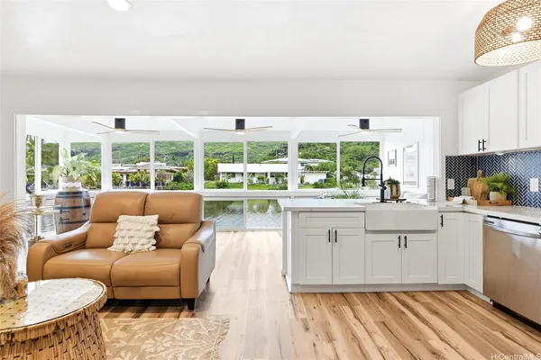 a living room with stainless steel appliances granite countertop a couch a stove a dining table and chairs with wooden floor