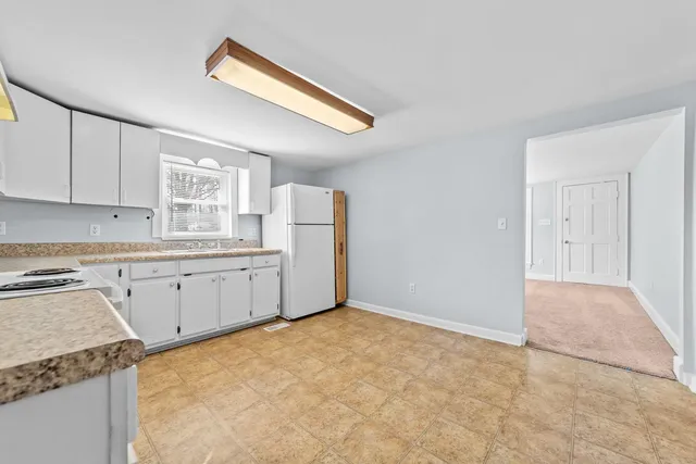 a kitchen with a refrigerator and white cabinets