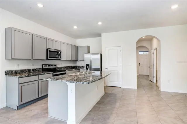 a kitchen with stainless steel appliances granite countertop a stove top oven a sink a refrigerator and white cabinets