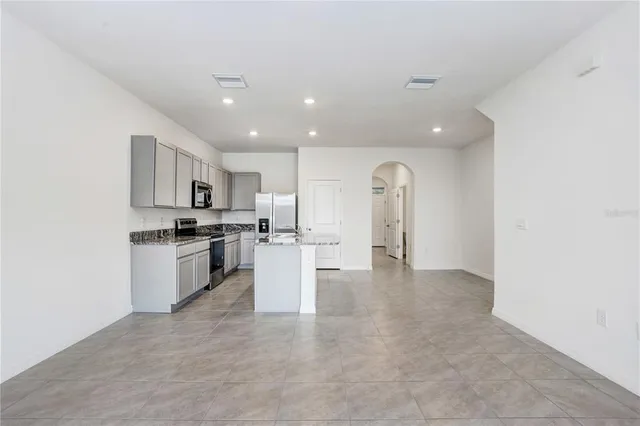 a view of open kitchen with white cabinets and stainless steel appliances