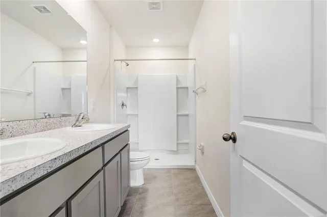 a bathroom with a granite countertop sink a toilet and shower