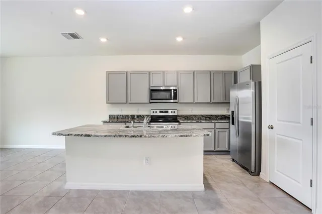 a kitchen with stainless steel appliances granite countertop a stove top oven a refrigerator and a granite counter tops