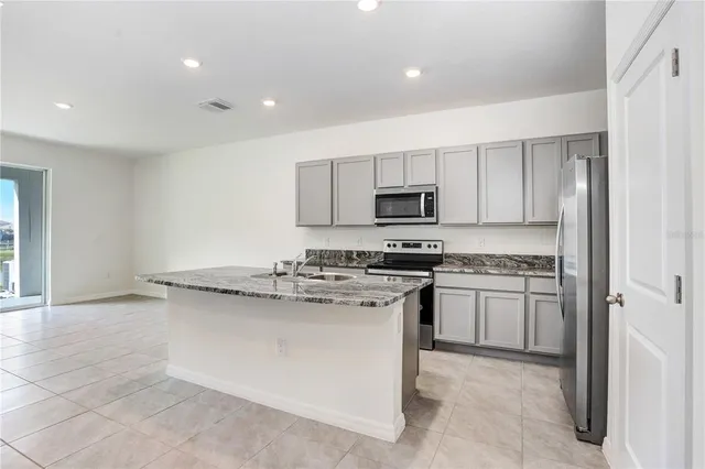 a kitchen with stainless steel appliances granite countertop a stove a sink and a refrigerator