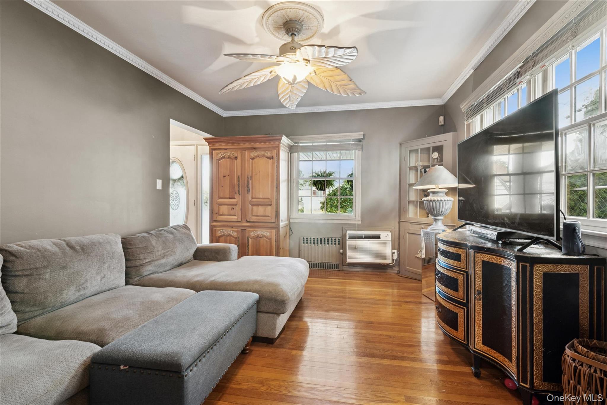 52-11 Redfield Street Queens, NY 11362 - Photo 15 of 32 Living room featuring ornamental molding, radiator heating unit, light wood finished floors, ceiling fan, and a wall unit AC