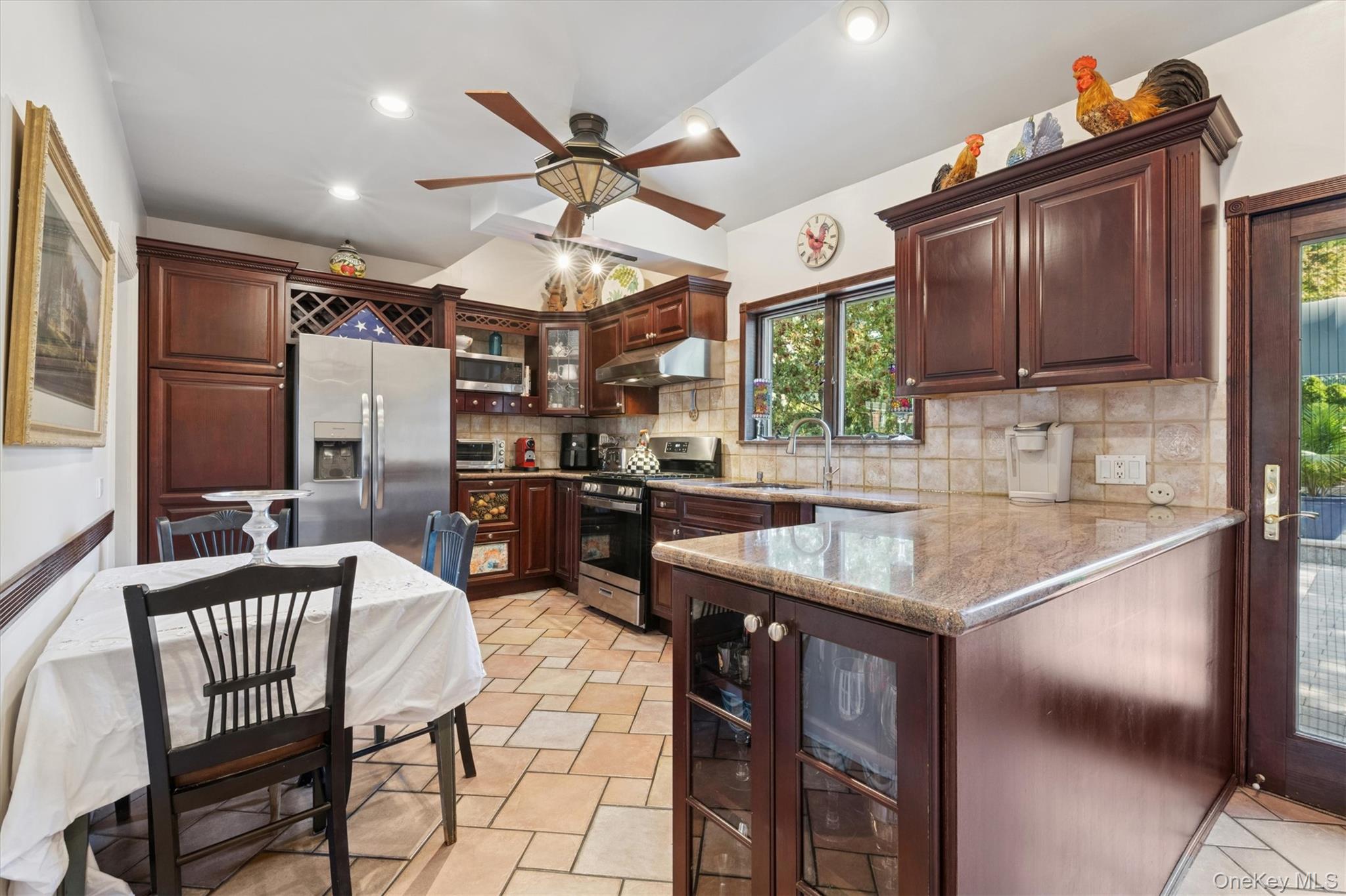 52-11 Redfield Street Queens, NY 11362 - Photo 16 of 32 Kitchen with glass insert cabinets, appliances with stainless steel finishes, tasteful backsplash, recessed lighting, and under cabinet range hood