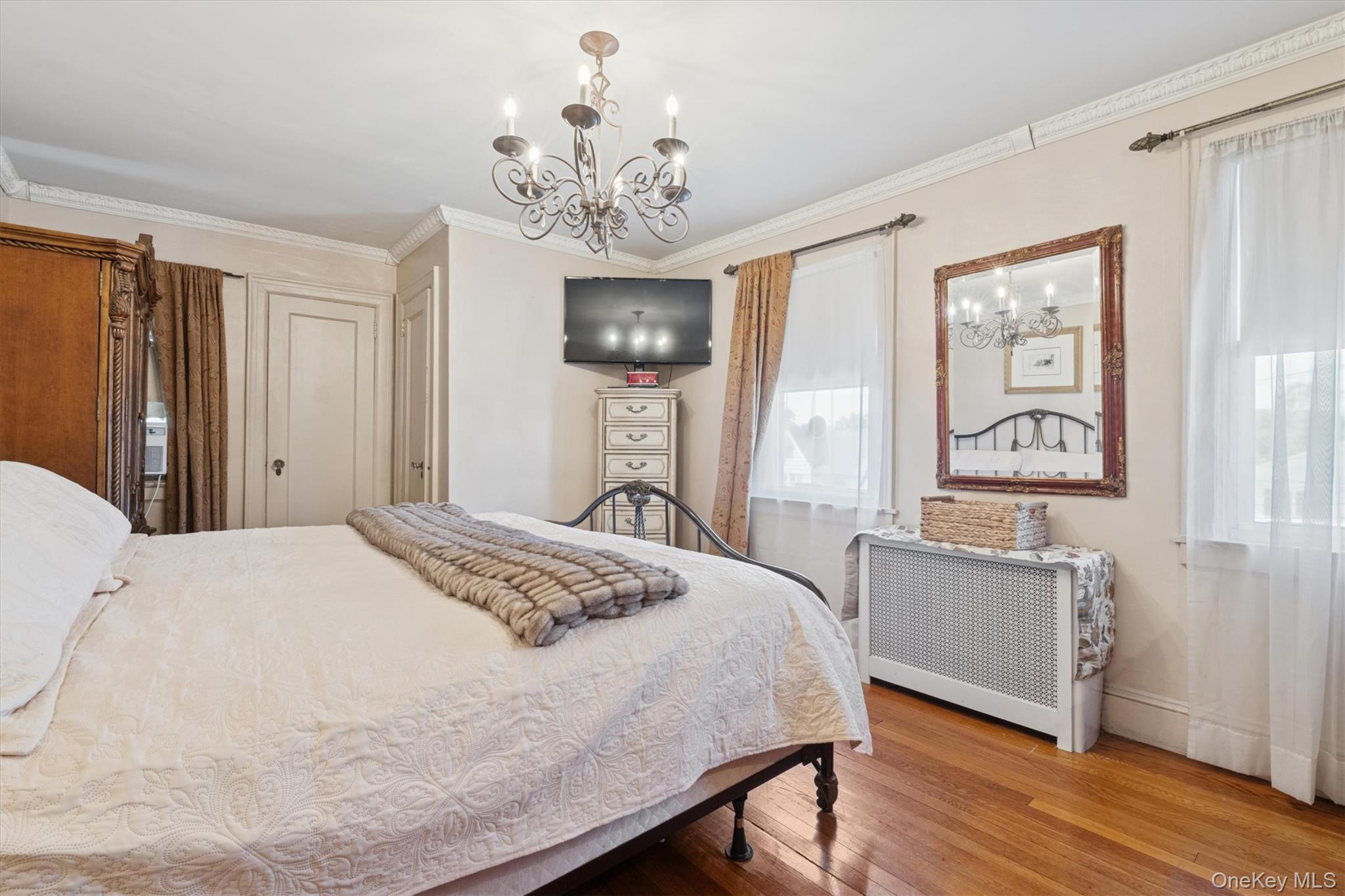 52-11 Redfield Street Queens, NY 11362 - Photo 22 of 32 Bedroom featuring a chandelier, radiator heating unit, ornamental molding, and wood finished floors