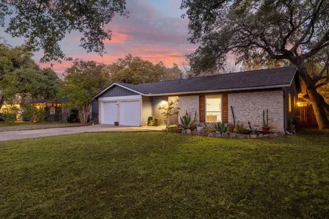 a front view of house with yard and trees in the background
