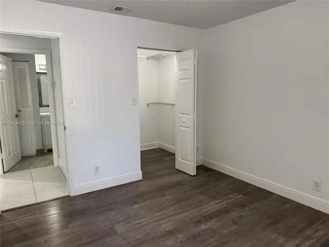 an empty room with wooden floor & mirror