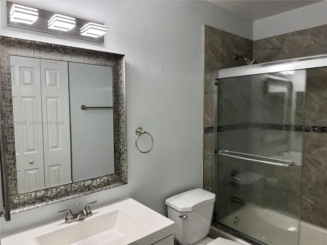 a bathroom with a shower sink mirror and toilet