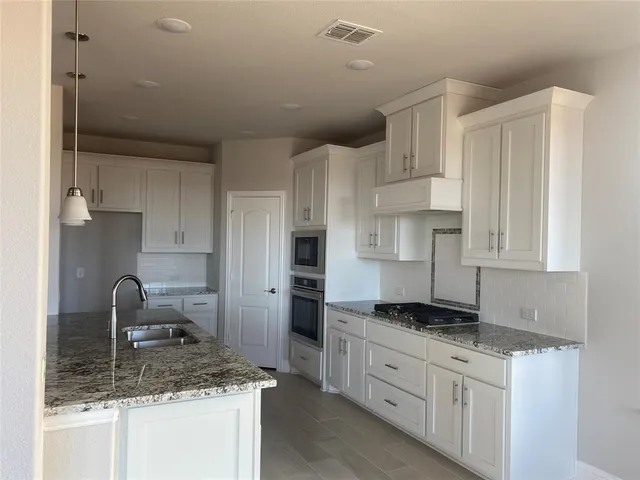a kitchen with granite countertop a sink stainless steel appliances and cabinets
