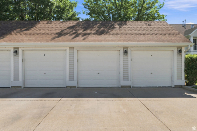 463 North 2400 West, Unit 7 Springville, UT 84663 - Photo 22 of 22 Individual garage doors with paneling, exterior lighting, light-colored siding, and a brown shingle roof