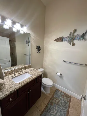 a bathroom with a granite countertop sink toilet and mirror