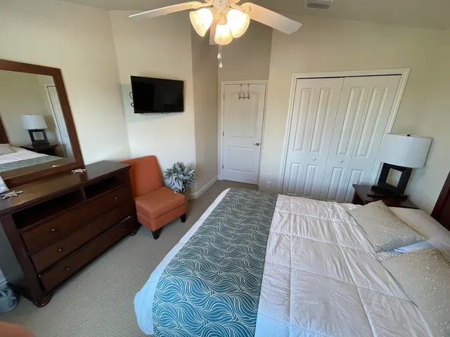 a bedroom with a bed a couch and a flat tv screen on dresser