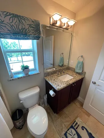 a bathroom with a granite countertop sink and a toilet