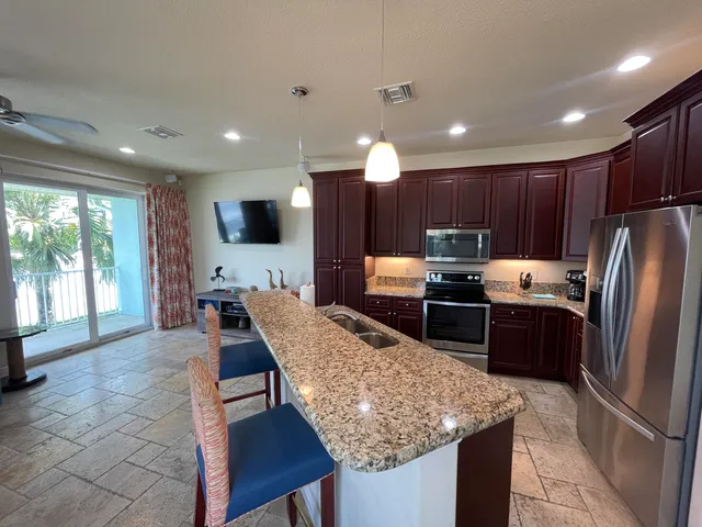 a kitchen with stainless steel appliances granite countertop a refrigerator a sink a stove a dining table and chairs