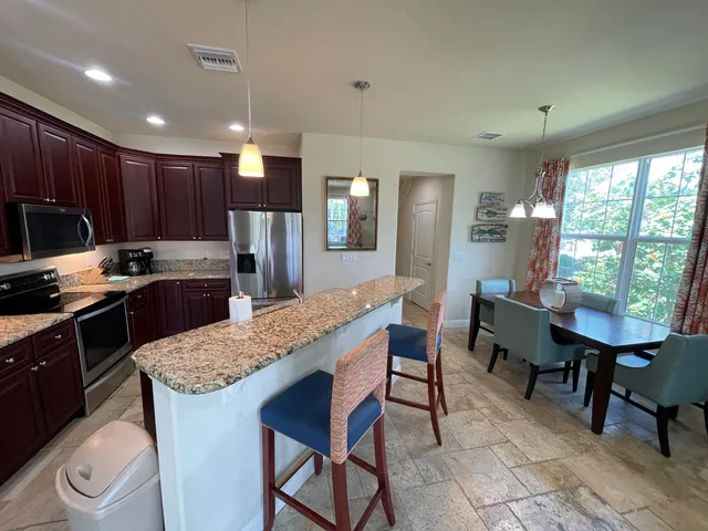 a kitchen with kitchen island granite countertop wooden cabinets and a refrigerator