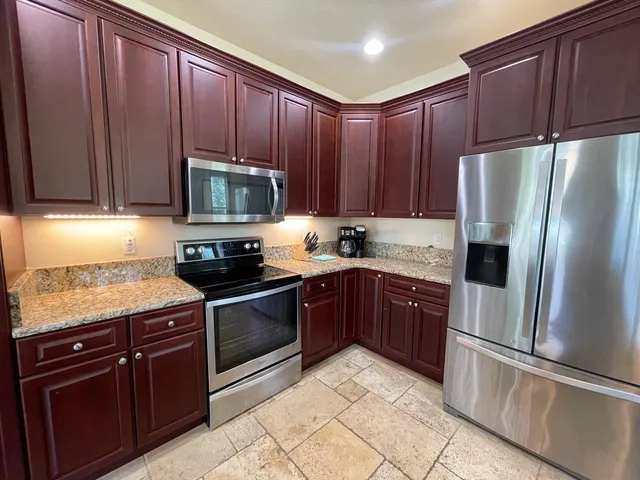 a kitchen with granite countertop wooden cabinets and stainless steel appliances