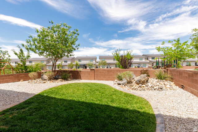 3157 Deseret Drive St. George, UT 84790 - Photo 22 of 24 Landscaped backyard featuring a central lawn area, gravel accents, and mature plantings