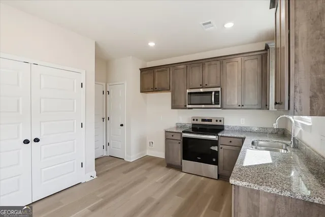 a kitchen with granite countertop a stove sink and refrigerator