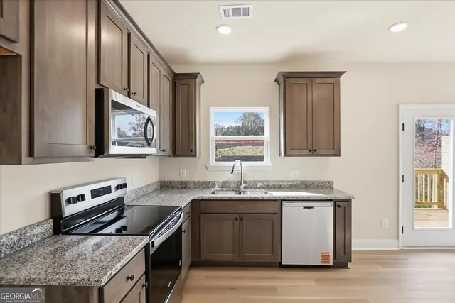 a kitchen with stainless steel appliances granite countertop a sink stove and cabinets
