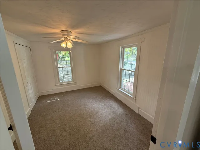 an empty room with windows and chandelier fan