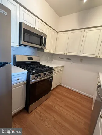a kitchen with granite countertop a refrigerator and a stove top oven